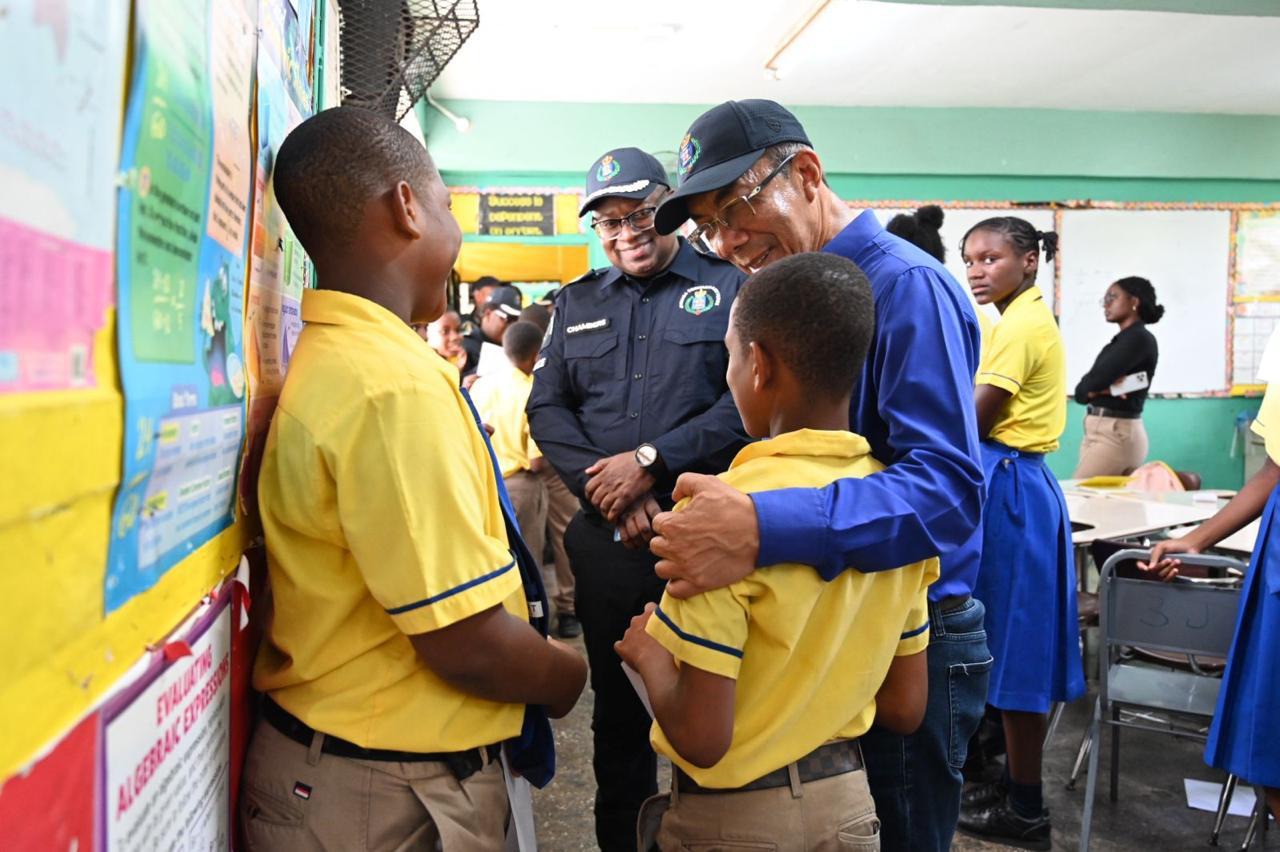Deputy Prime Minister and Minister of National Security and Peace, the Hon. Dr Horace Chang and Assistant Commissioner of Police, Howard Chambers, interact with students of the Constant Spring Primary and Infant School, while visiting the institution after touring Area 5 Headquarters in Constant Spring, on Thursday, June 4.