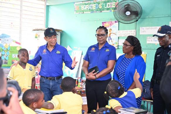 Deputy Prime Minister and Minister of National Security and Peace, the Hon. Dr. Horace Chang (left), Permanent Secretary, Ambassador Alison Stone Roofe (centre) and Commissioner of Police, Dr. Kevin Blake (right) address Vice Principal of the Constant Spring Primary School, Michelle Wiggins, and Grade one students at a recent visit to the St. Andrew-based institution.