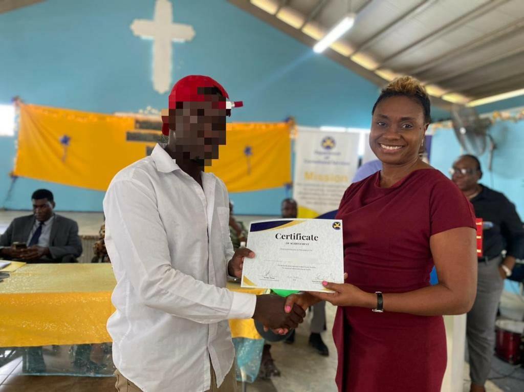 Minister of State in the Ministry of National Security, the Hon. Juliet Cuthbert-Flynn presents a certificate of achievement in academics to one of the eighty inmates at the St. Catherine Adult Correctional Centre during their Awards and Recognition Ceremony at the facility today (December 11).